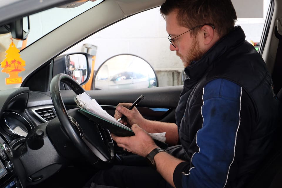 MB Services mechanic writing on clipboard during mot test